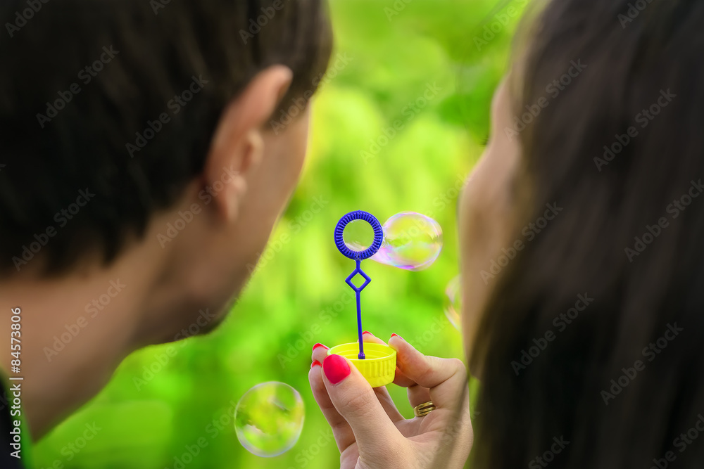 young couple having fun with soap bubbles in the park young couple having fun with soap bubbles in the park
