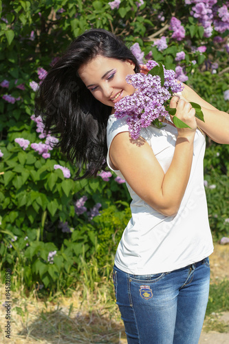 beautiful young girl near the lilac, beautiful purple flowers. warm summer day photo