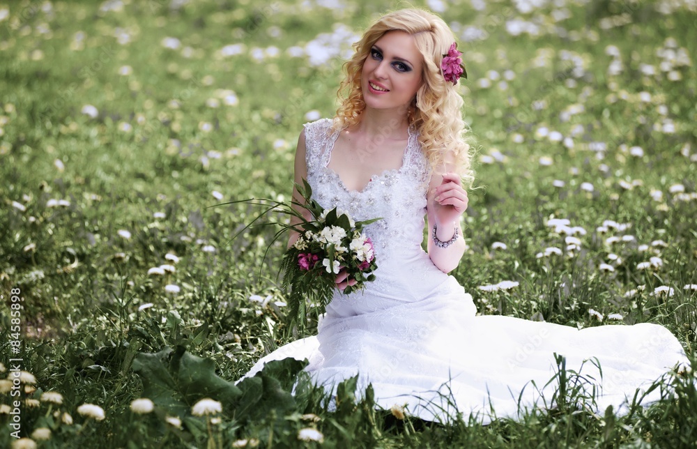 Beautiful young bride in white dress sits field in summer green park Beautiful young bride in white dress sits field in summer green park