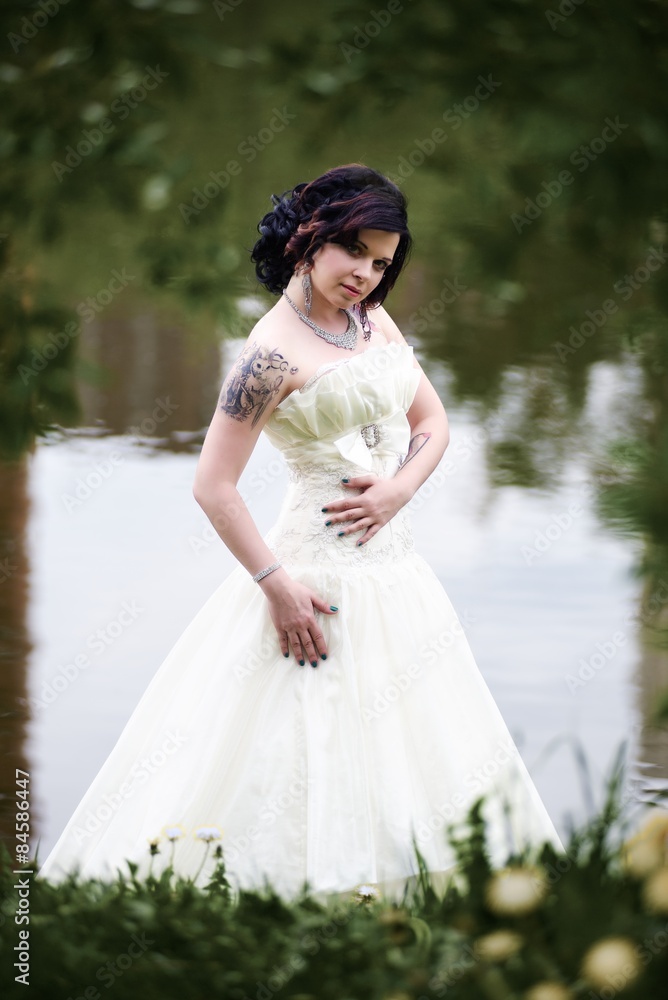 Beautiful young bride in white dress near lake in summer green park Beautiful young bride in white dress near lake in summer green park