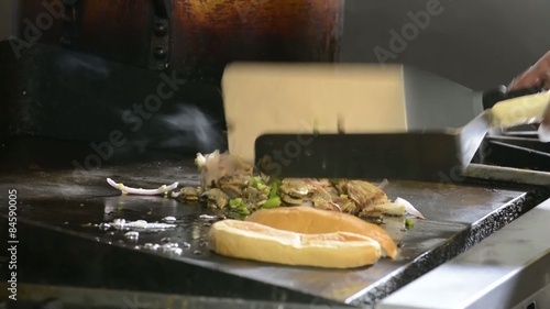 A Philly steak sandwich simmering on a commercial grill
