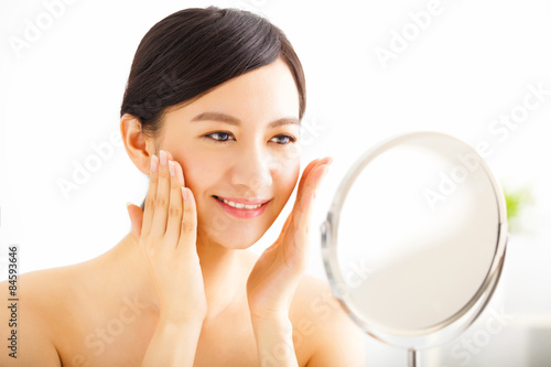 Happy young woman looking on mirror