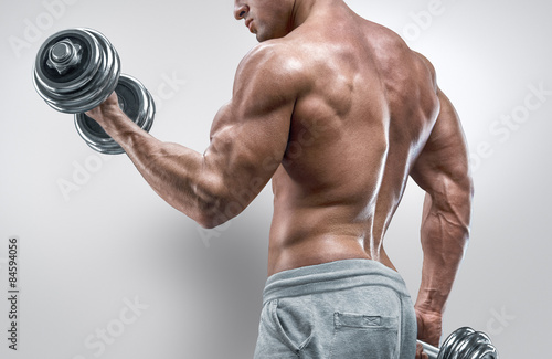 Power athletic man in training pumping up muscles with dumbbells