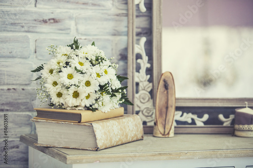 Fototapeta Naklejka Na Ścianę i Meble -  Wedding bouquet of daisies on a stack of books