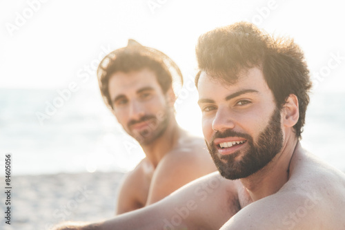 Couple male friends on the beach at sunset