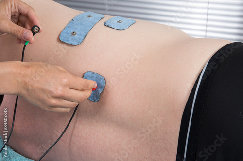 Man with electrostimulator electrodes on his body