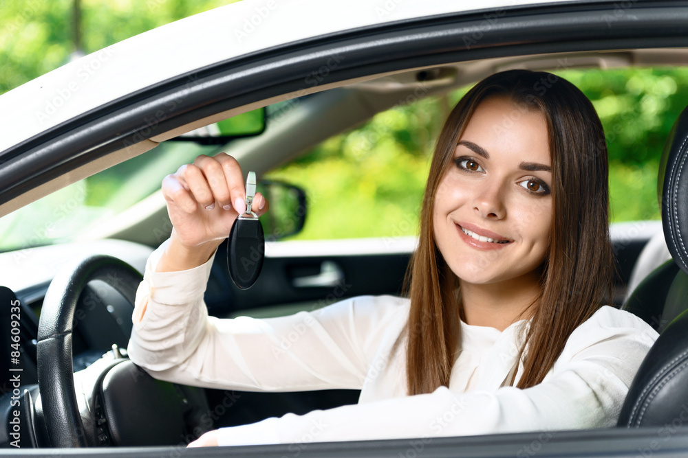 Pretty girl sitting inside car and holding key