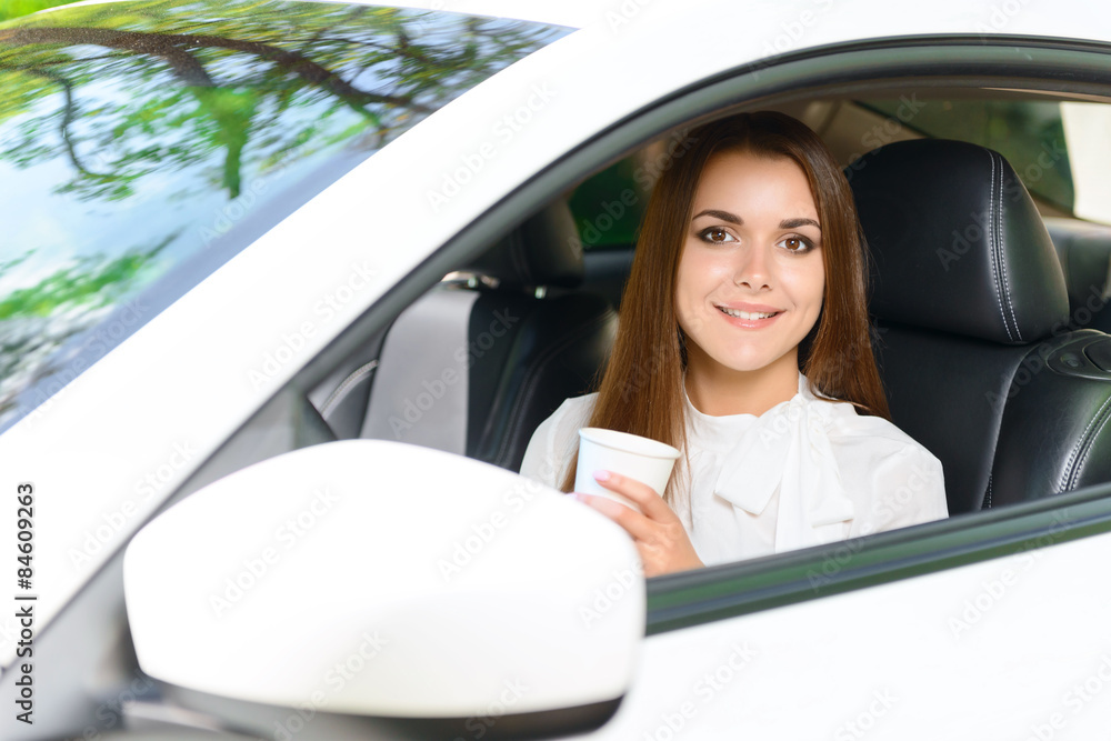 Smiling girl in car with cup of coffee Smiling girl in car with cup of coffee