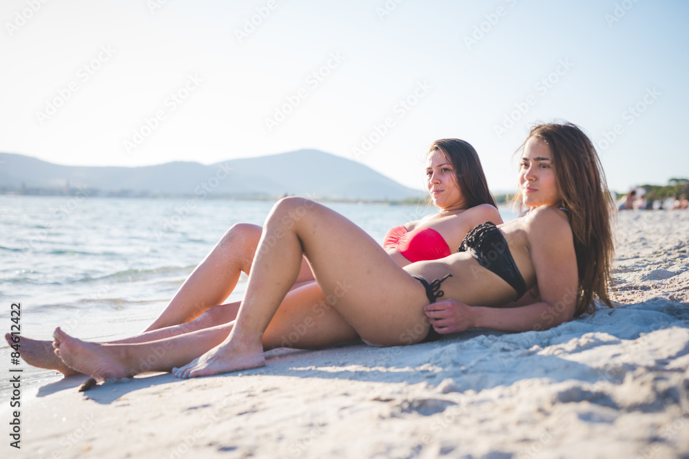two beautiful young women lying in the sand at the beach two beautiful young women lying in the sand at the beach