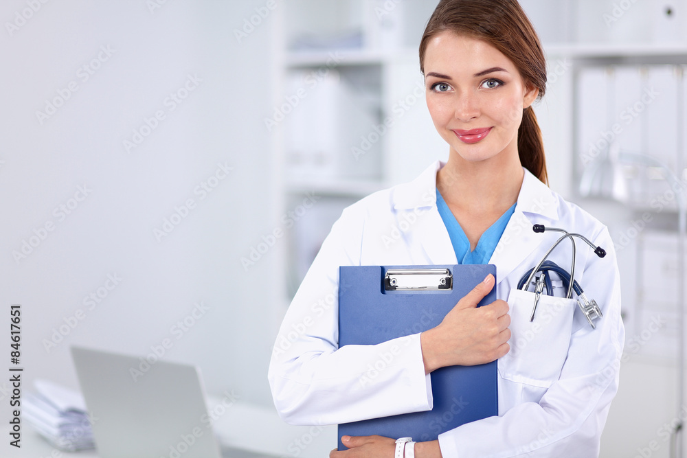Smiling female doctor with a folder in uniform standing at Smiling female doctor with a folder in uniform standing at