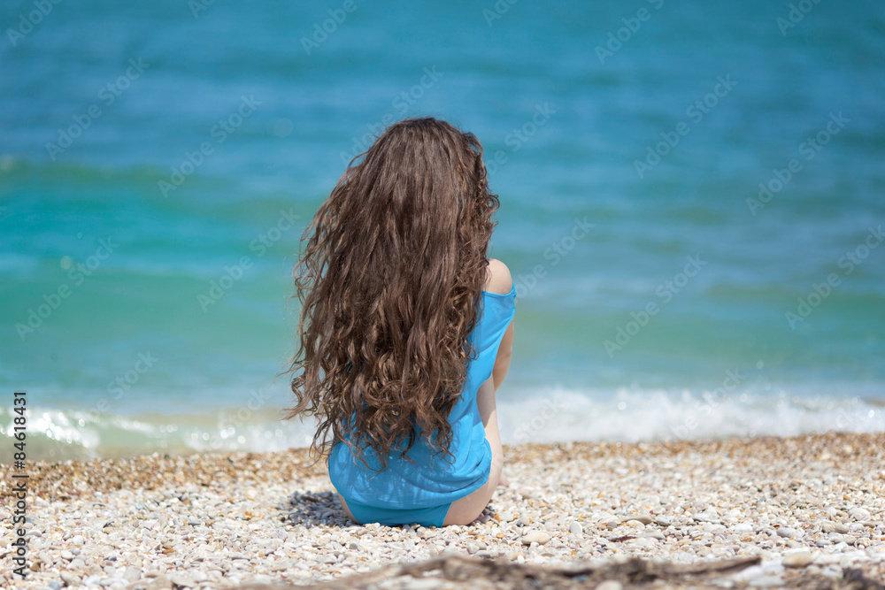 Long hair. Young attractive woman relax on the beach by blue wat foto