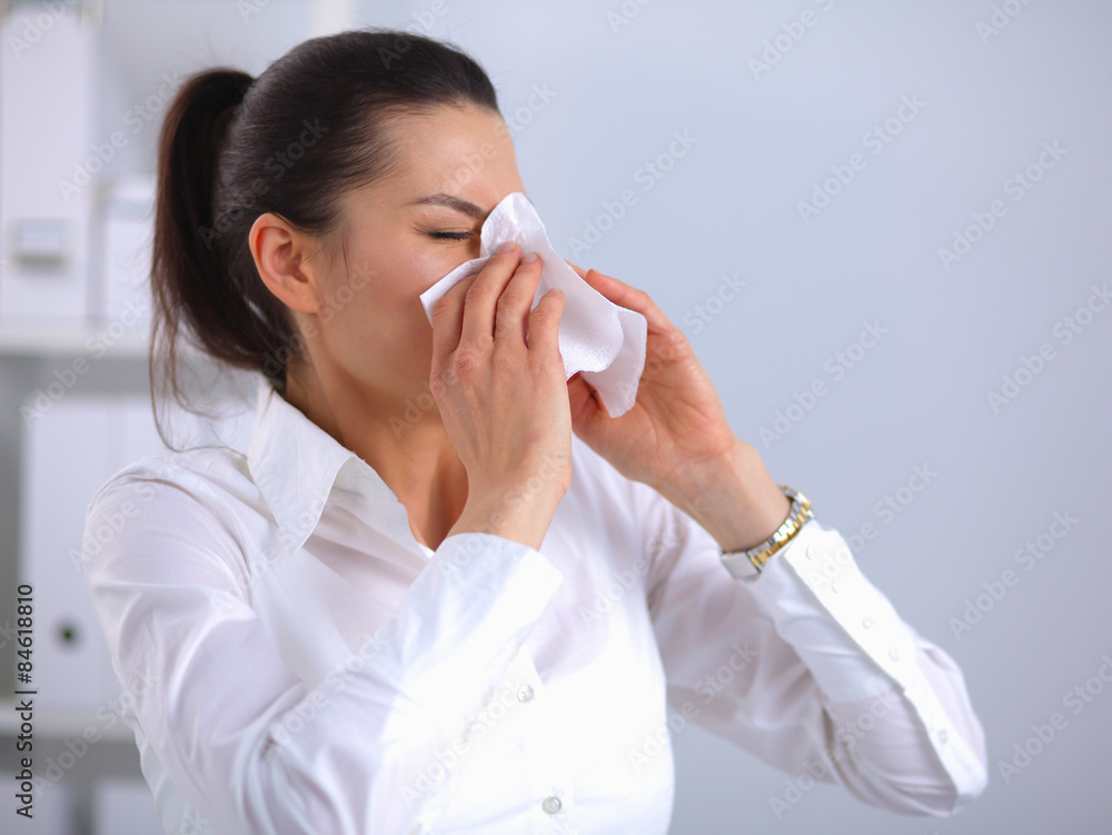 Young businesswoman blowing her nose, sits at the desk Young businesswoman blowing her nose, sits at the desk