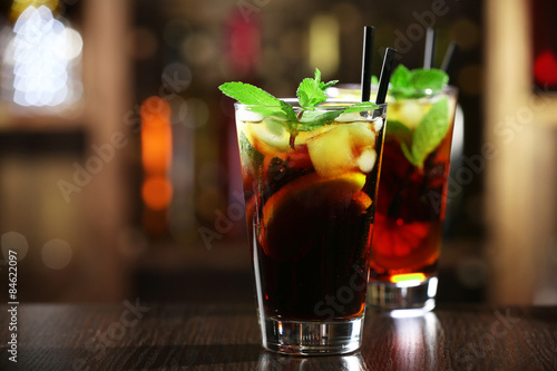 Glass of cocktail in bar on bright blurred background