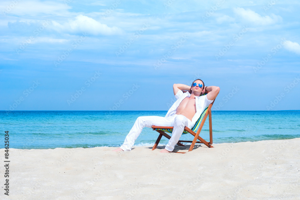 Young, fit, athletic and handsome man relaxing on a summer beach Young, fit, athletic and handsome man relaxing on a summer beach
