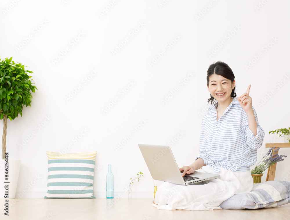 部屋でノートパソコンを使う女性