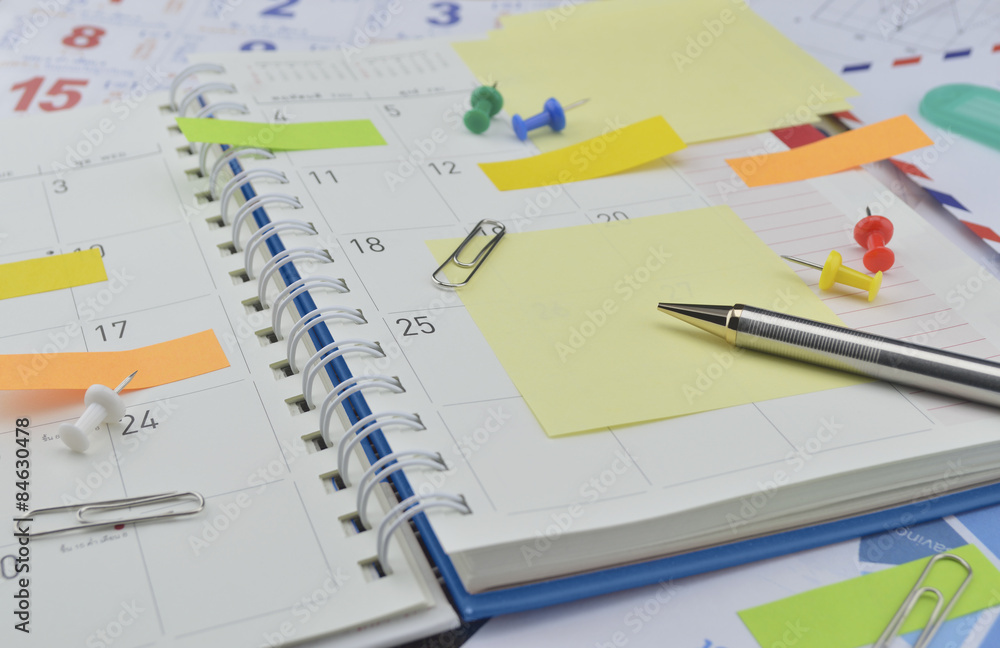 Pen with post It notes and pin on business diary page Pen with post It notes and pin on business diary page