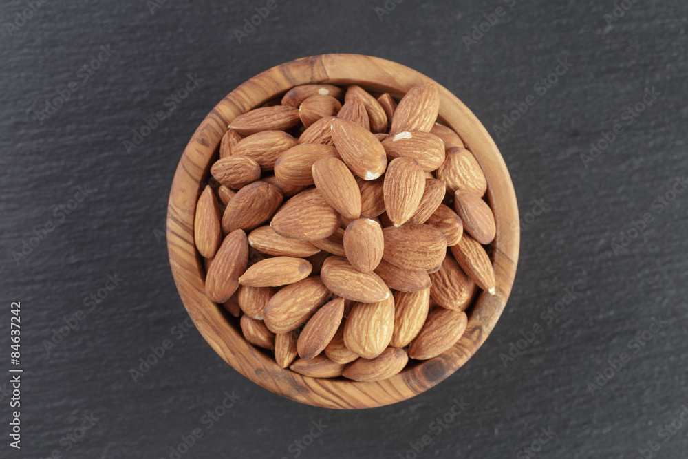 roasted almonds in bowl on slate background roasted almonds in bowl on slate background
