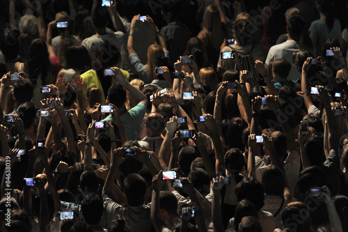 Excited youngsters attending a show, applauding and taking videos vith cell phones