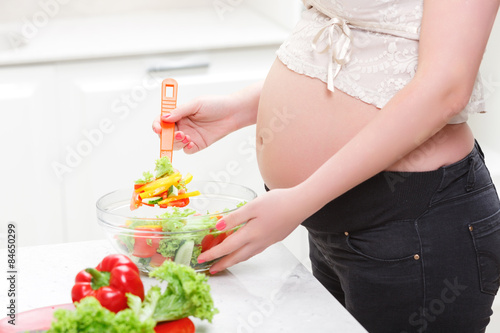 Pregnant woman cooking salad
