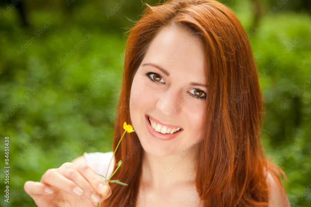 Lachende junge Frau mit Blume in der Hand