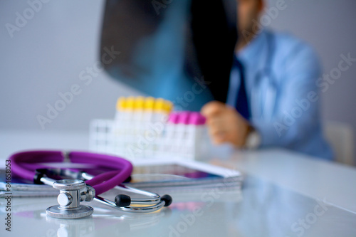 Medical doctor sitting at table and looking patients roentgen