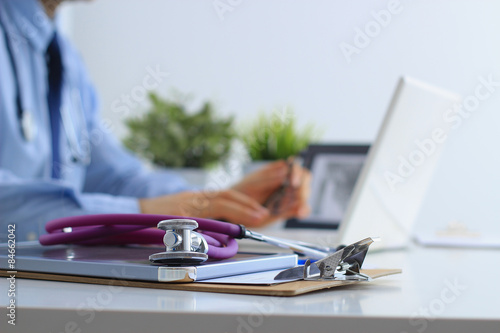 Male doctor using a laptop, sitting at his desk