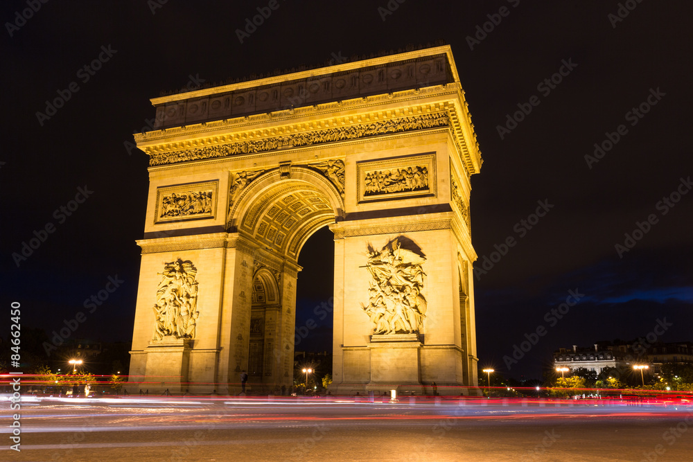Illuminated Arc de Triomphe with light rails of passing traffic in Paris