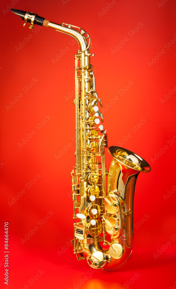 Naklejka premium Alto saxophone in full length on red background 