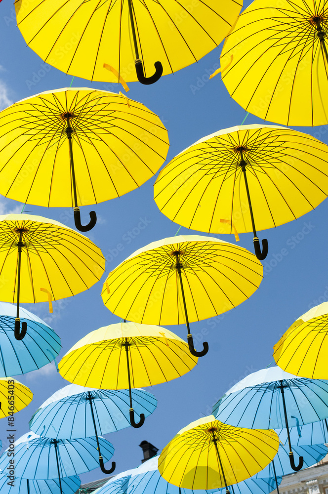 Yellow and blue umbrellas under a cloudy sky.
