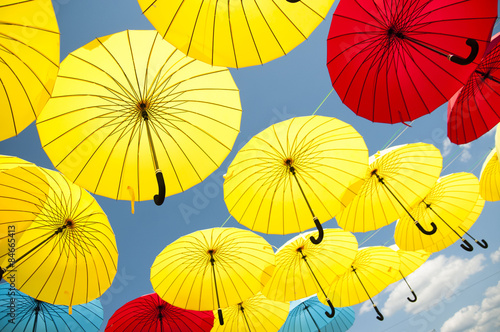 Yellow and blue  red umbrellas under a cloudy sky.