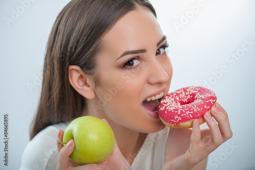 Beautiful young woman with healthy and unhealthy food