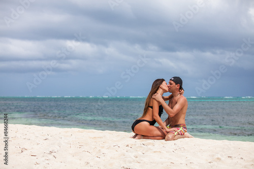Young couple sitting together on a sand by ocean