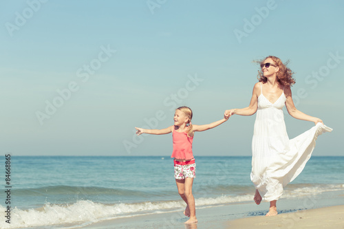 Mother and daughter playing on the beach at the day time.