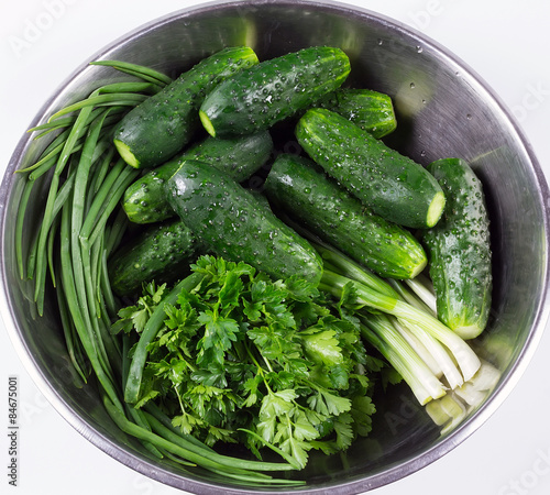 Fresh cucumbers and fresh herbs in a bowl isolated