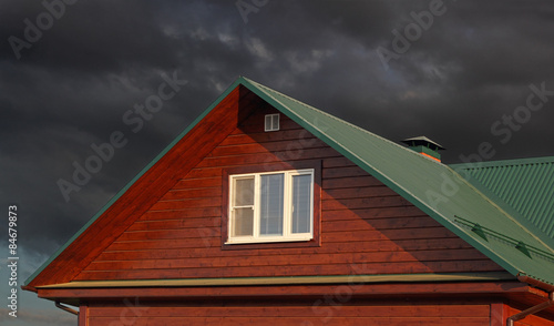Green metal roof under dark cloudy sky