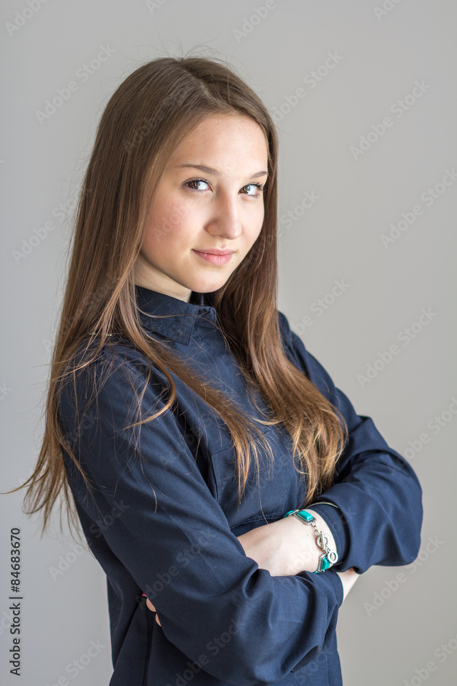 Fototapeta premium Girl in shirt smiling with arms crossed over gray background