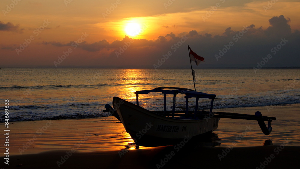 einsames Fischerboot am Sandstrand vor untergehender Sonne
