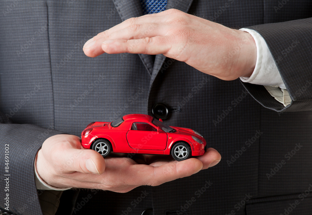 Businessman holding a  red toy car