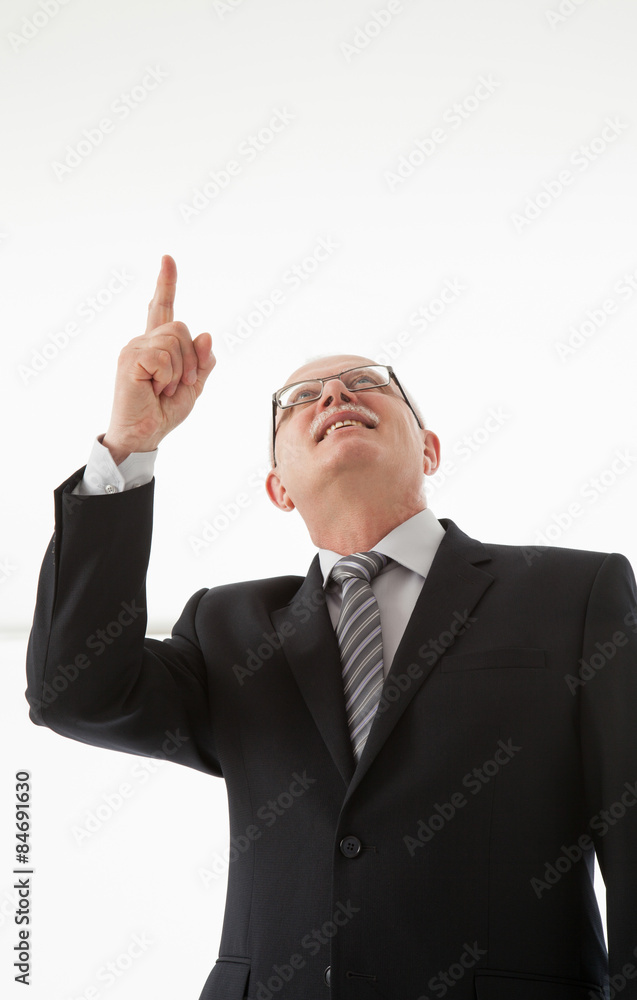 Smiling mature businessman looking and indicating up Smiling mature businessman looking and indicating up