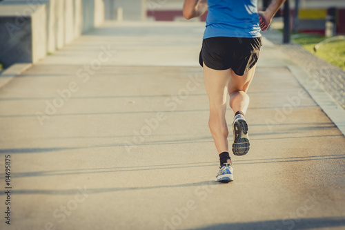 healthy sport man with athletic legs running in city urban park