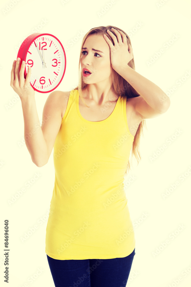 Attractive young woman in yellow top holding a clock. Attractive young woman in yellow top holding a clock.