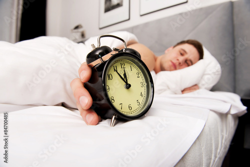 Man with alarm clock in bedroom. photo
