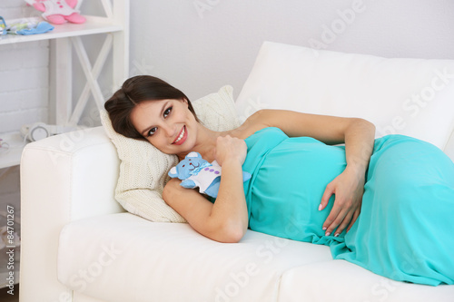 Pregnant woman lying on sofa in room