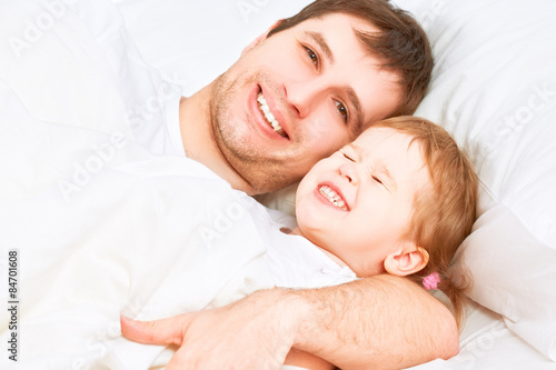 Happy family father and child baby daughter sleeping in bed