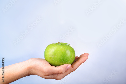Female hand with apple on colorful background