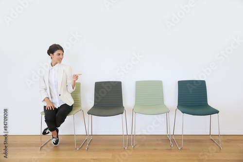 Brunette girl sitting on chair pointing at message