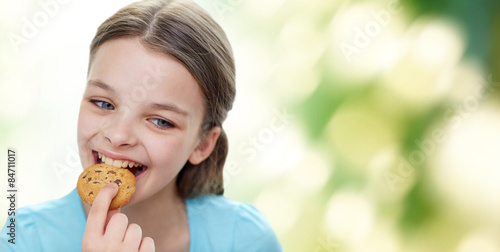 smiling little girl eating cookie or biscuit