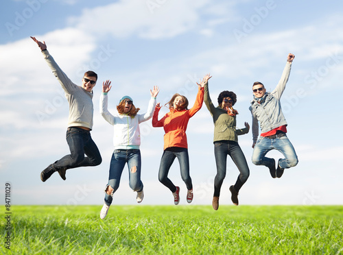 smiling friends in sunglasses jumping high