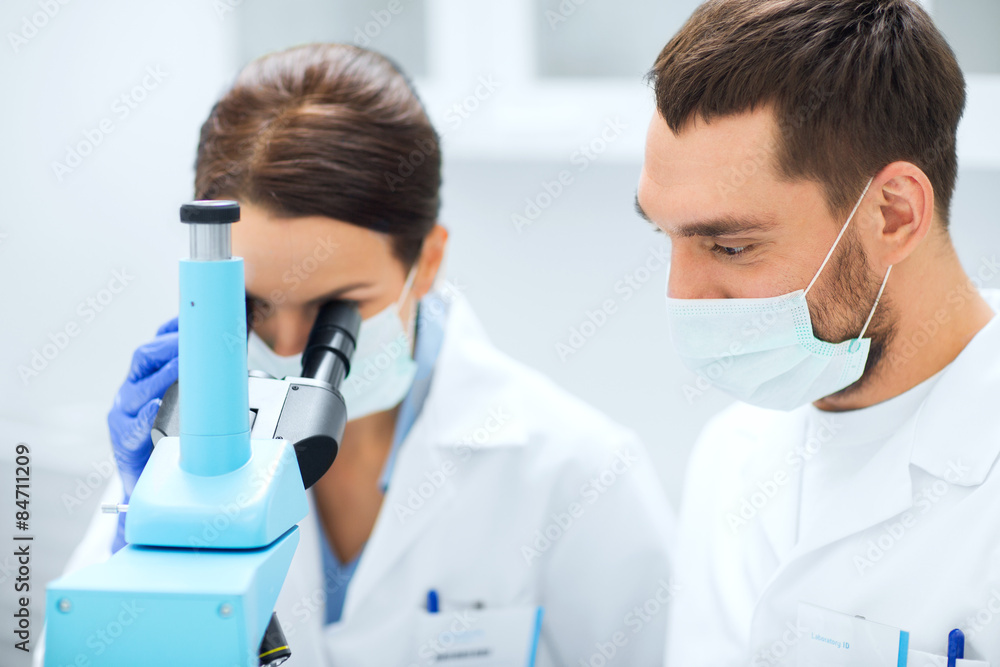 scientists in masks looking to microscope at lab scientists in masks looking to microscope at lab