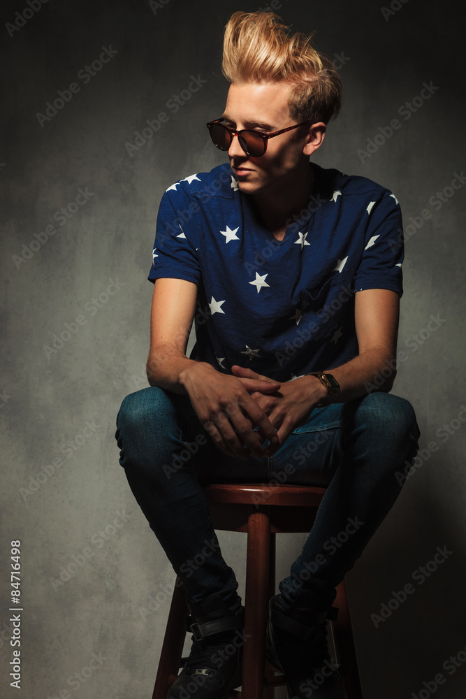 Obraz premium young fashion man is resting on a stool